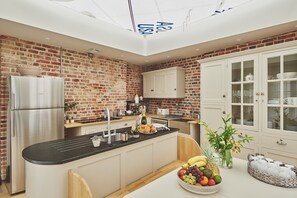 Una cocina moderna con pared de ladrillo, electrodomésticos de acero inoxidable y una isla central con frutas y flores.