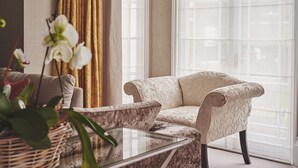 Un salon avec un canapé, une table basse en verre et une grande fenêtre avec des rideaux.
