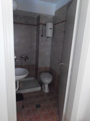 A small bathroom with a toilet, sink, and shower. - Julieta's House (Alonissos)