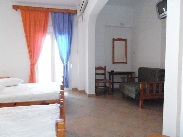 A room with two beds, a chair, a small table, and a mirror on the wall. - Julieta's House (Alonissos)