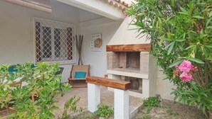 Un espace extérieur aménagé avec un banc en bois, un four en briques et des plantes en pot.