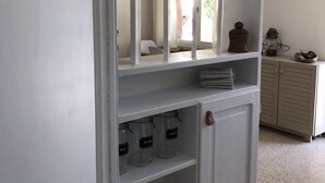 Un meuble de rangement blanc, doté d’étagères où se trouvent des bocaux étiquetés « PÂTES » et « SUCRE ».