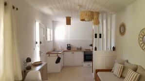 Une cuisine de taille réduite avec des meubles blancs, un plan de travail en bois et un luminaire suspendu.