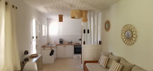 A compact kitchen with white cabinets, a wooden countertop, and a hanging light fixture.