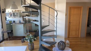 Una cocina moderna con una isla central, una escalera en espiral y una puerta de madera.