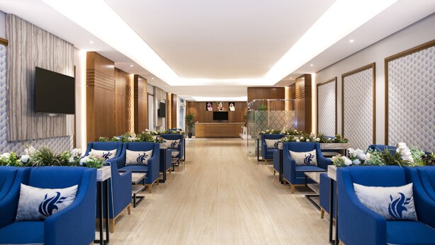 Un vestíbulo de hotel con una mesa de recepción, sofás azules y suelo de madera.