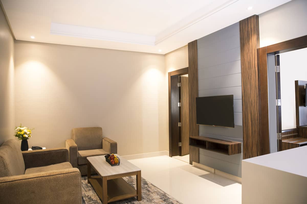A modern living room with a sofa, coffee table, and a flat-screen TV mounted on a wooden wall.