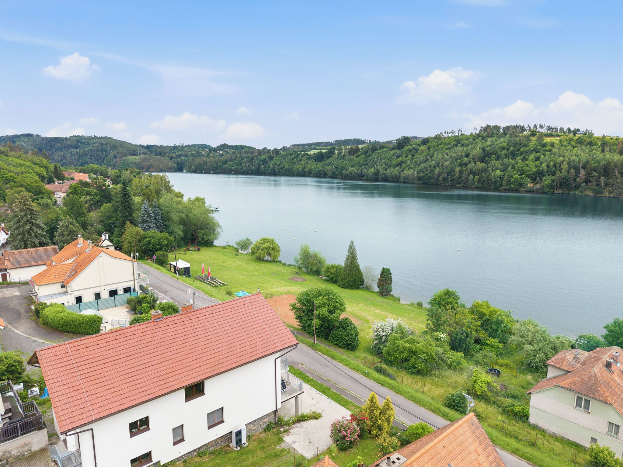 A residential area with houses, a road, and a lake.