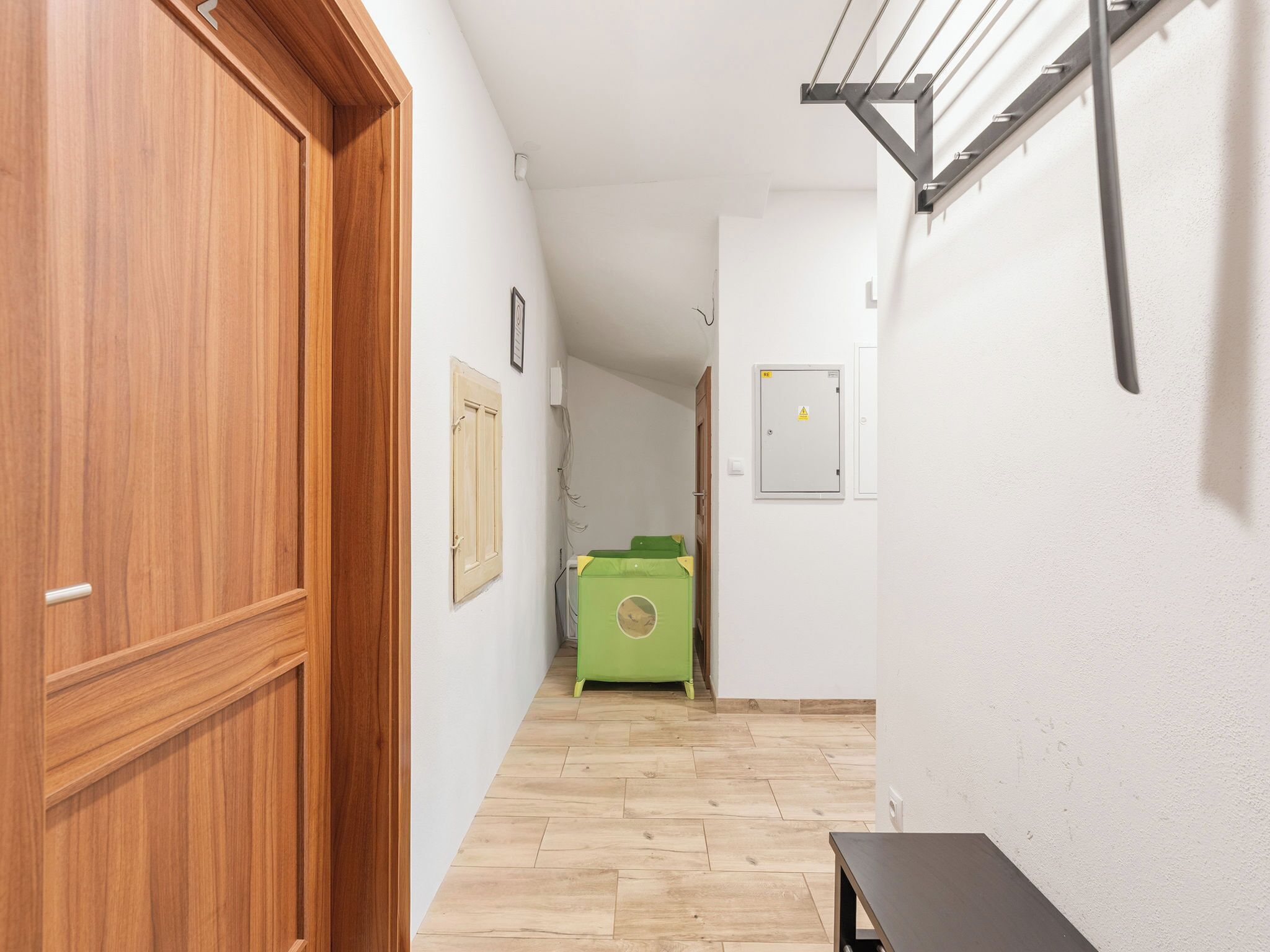 Un couloir avec des portes en bois, un meuble vert et une table noire.