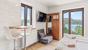 A bedroom with a bed, a chair, a table, a TV, and a view of a lake. - Županovice by Interhome (Zupanovice)