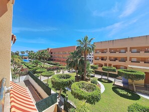 Cortile di un hotel con piscina, palme e un edificio con diversi balconi.