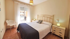 A bedroom with a bed, bedside tables, a chair, and a window with curtains. - Nassau - Apartment with terrace and pool in Vera Playa (Vera playa)