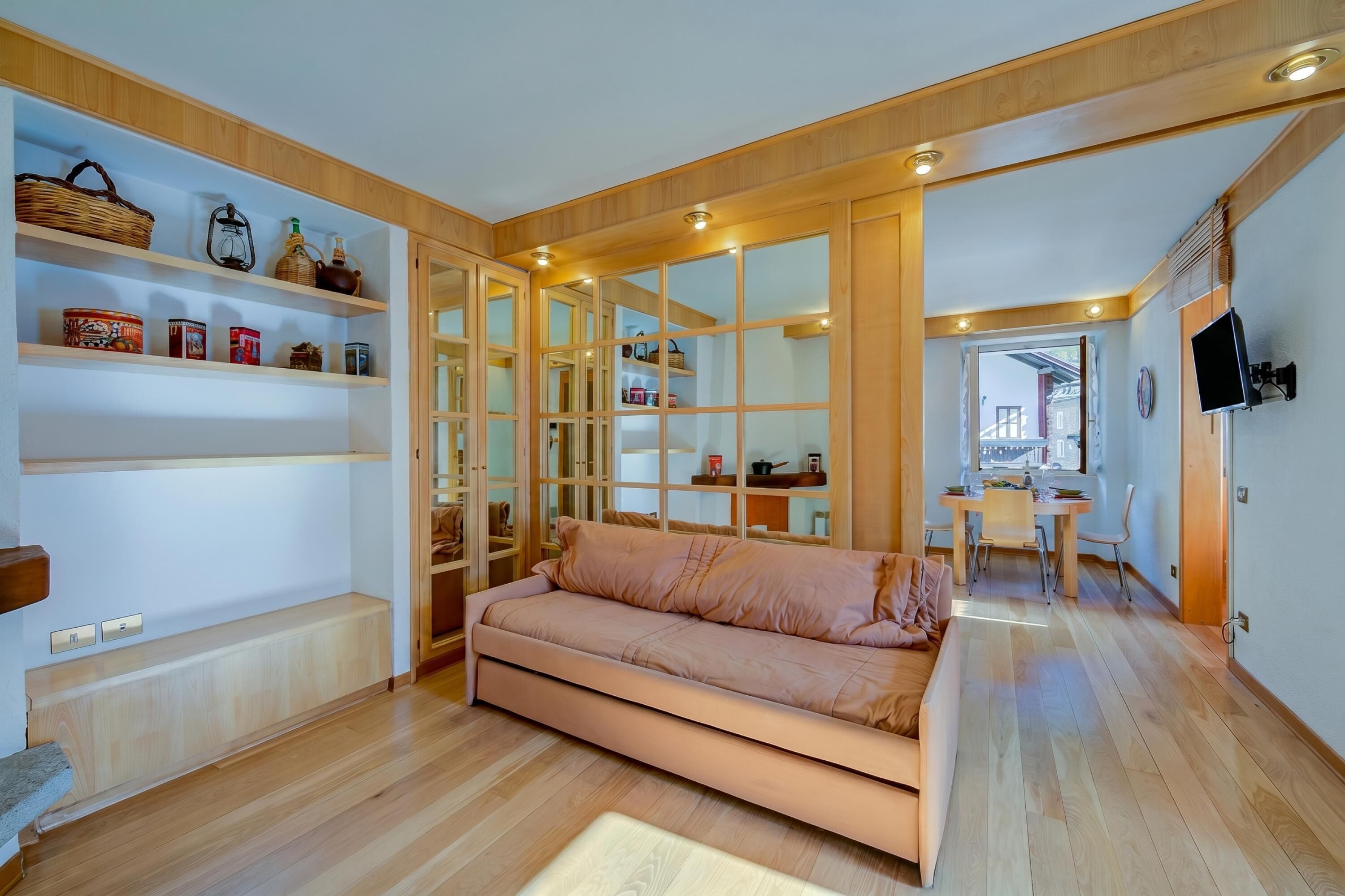 Una sala de estar moderna con un sofá, estantes de madera y un comedor.