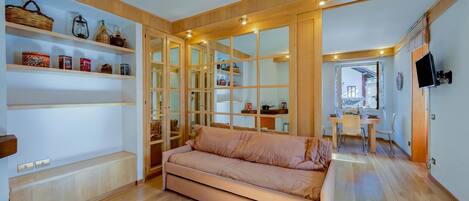Una sala de estar moderna con un sofá, estantes de madera y un comedor.