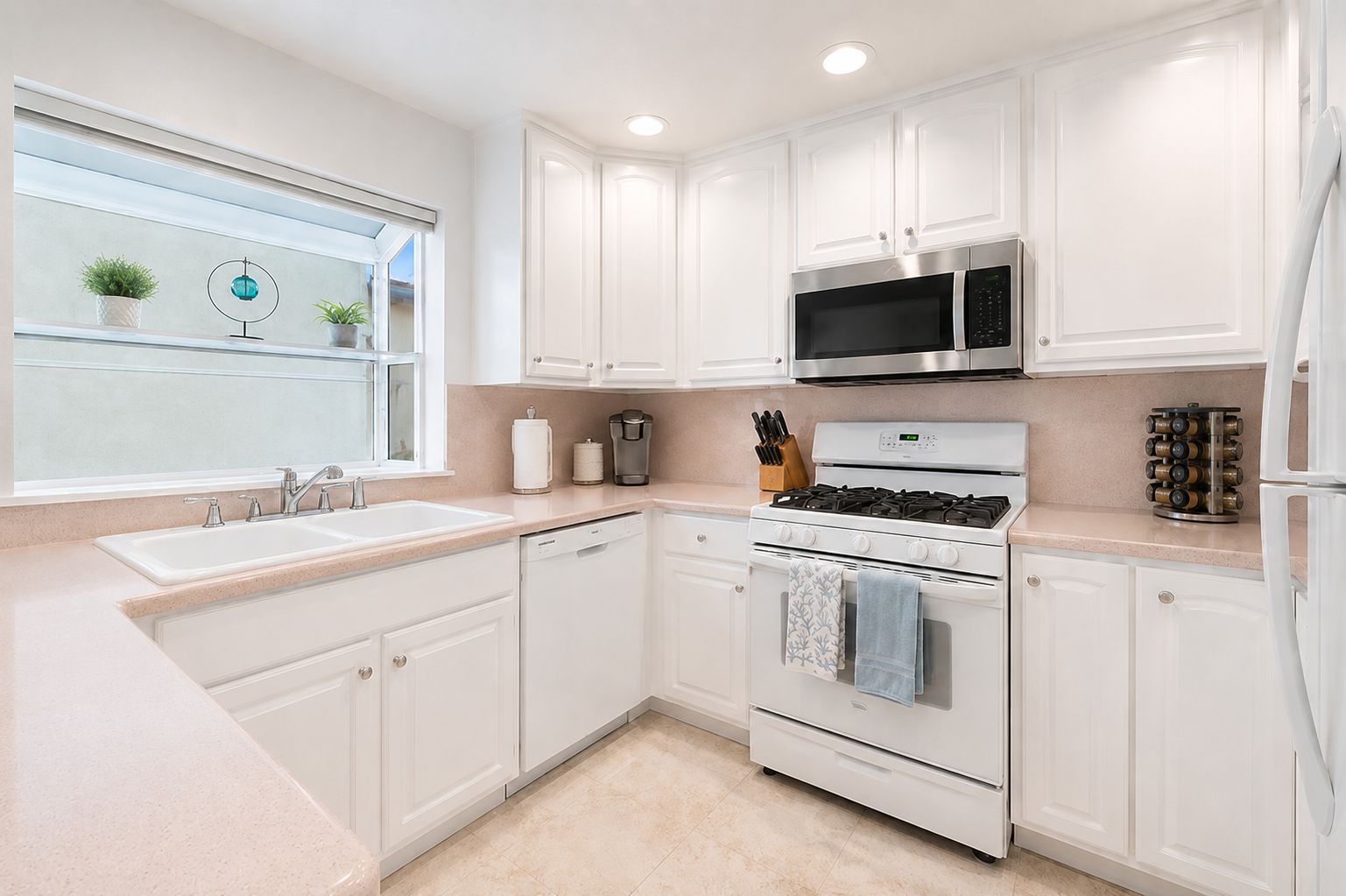 A modern kitchen with white cabinetry, a stainless steel microwave, a gas stove, and a dishwasher.