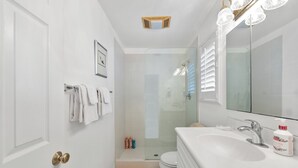 A bathroom with a white sink, a mirror, a shower, and a toilet. - Luxury Beach House 99 Steps from Sand, Pet-friendly (Ventura)