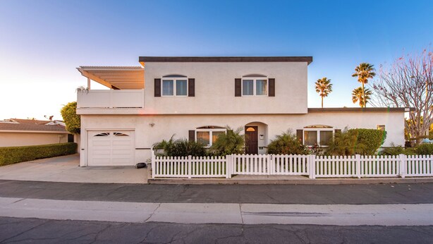 A two-story house with a white picket fence, a garage, and a small porch. - Luxury Beach House 99 Steps from Sand, Pet-friendly (Ventura)