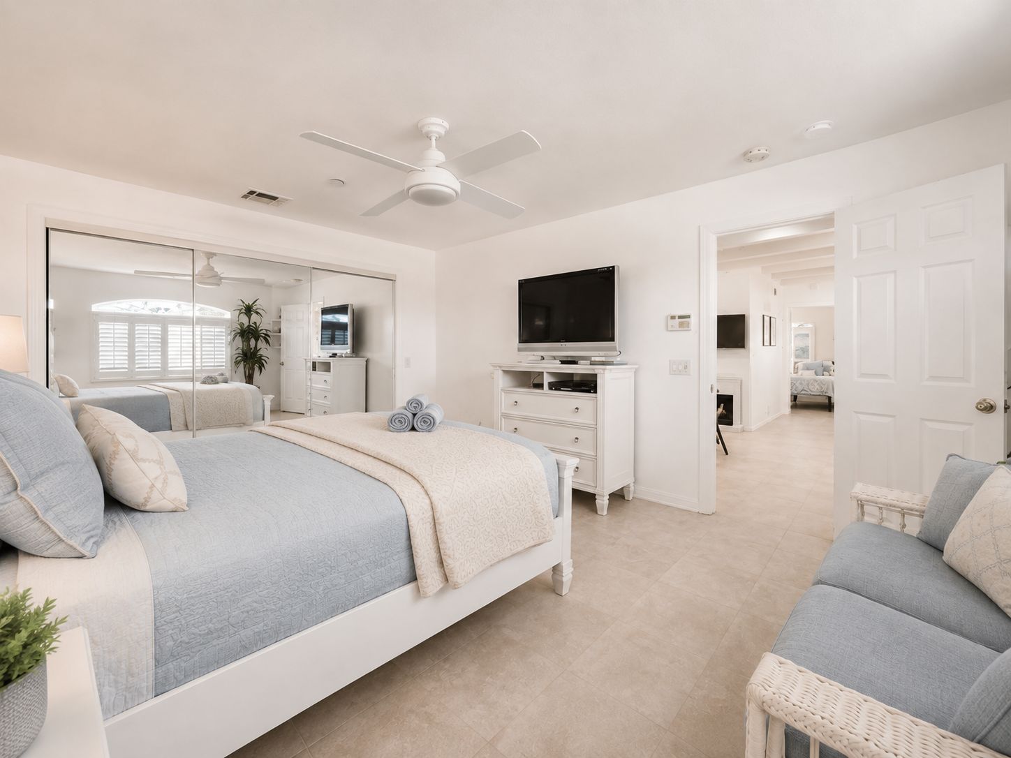 A bedroom with a bed, a television, a dresser, and a ceiling fan.