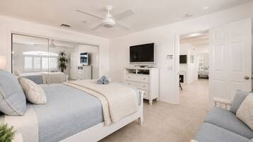 A bedroom with a bed, a television, a dresser, and a ceiling fan.