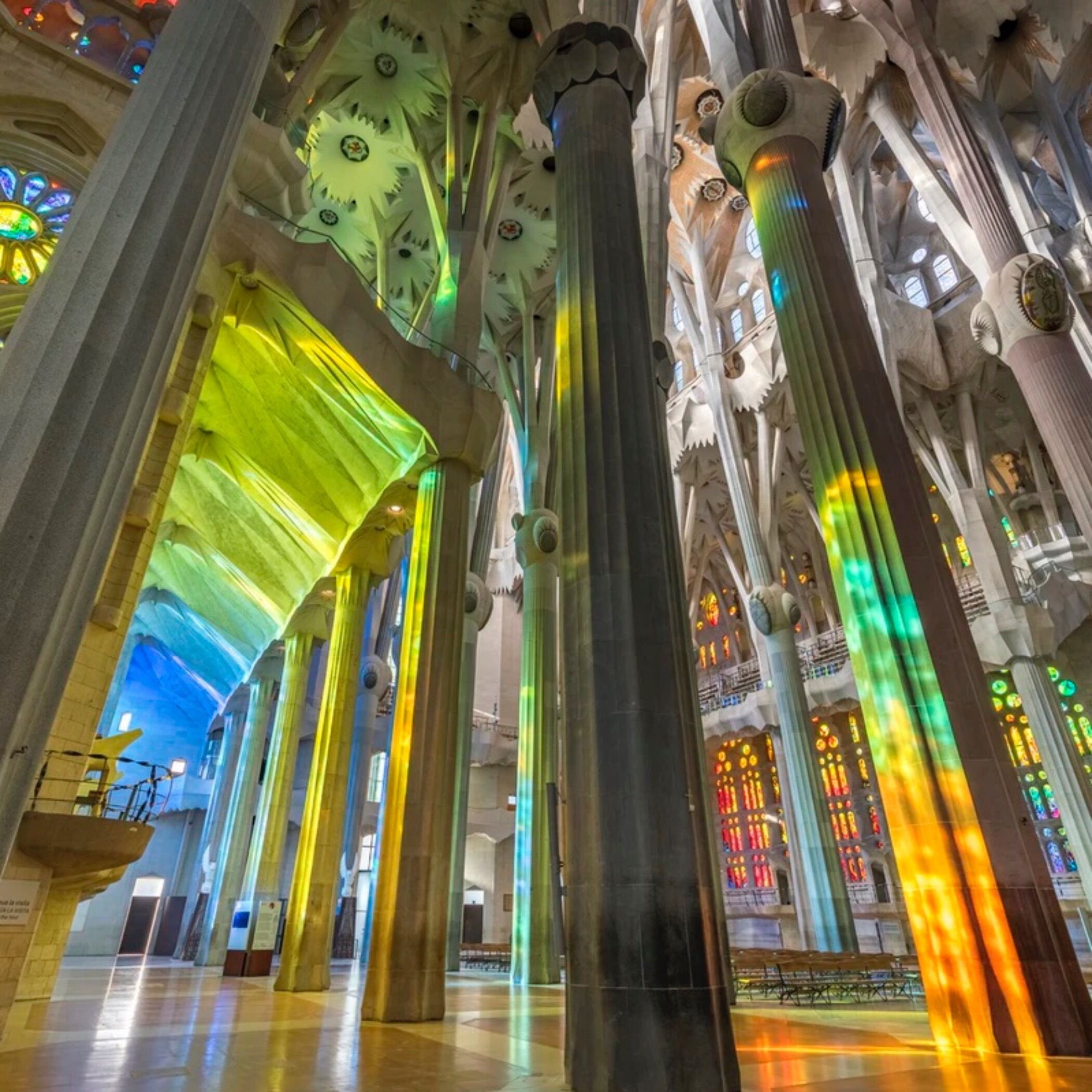 Un interior espacioso con techos altos y amplias columnas, que presenta un diseño arquitectónico moderno con patrones geométricos y un tragaluz.