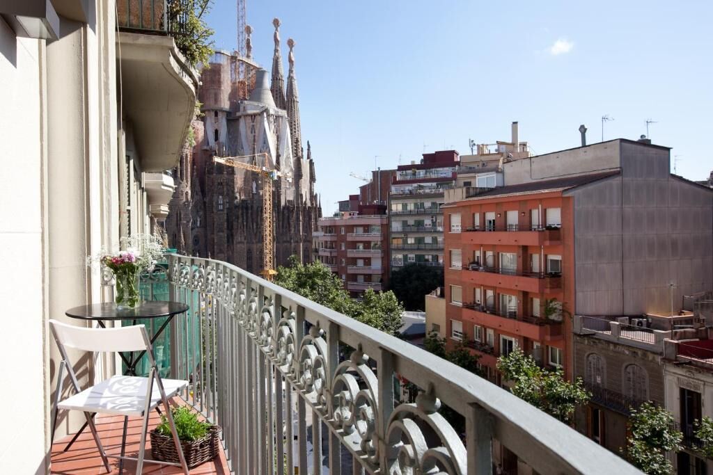 Un balcon offrant une vue sur un bâtiment historique et, au loin, sur des immeubles modernes.