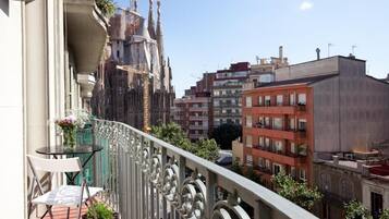 Un balcon offrant une vue sur un bâtiment historique et, au loin, sur des immeubles modernes.
