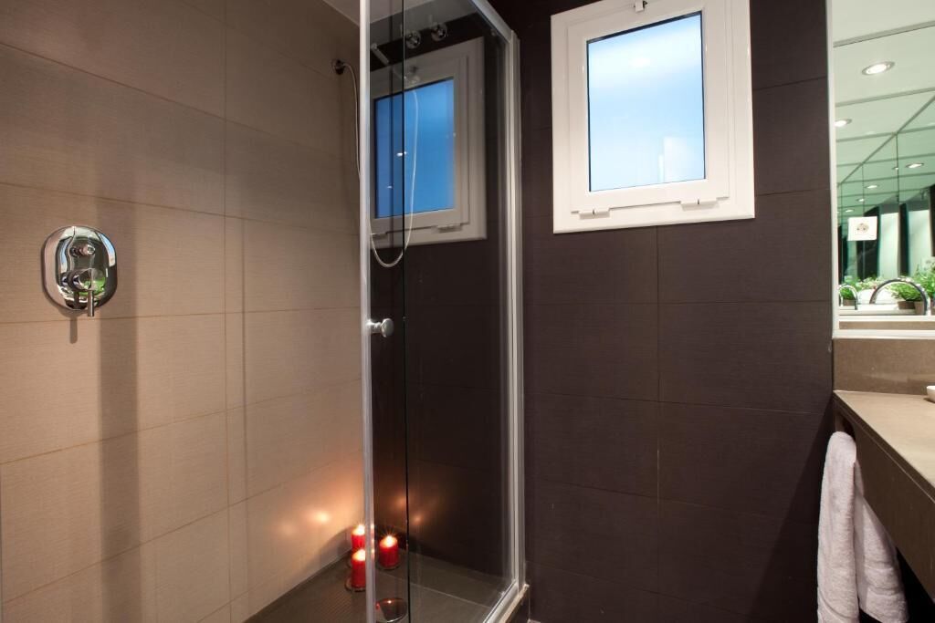 A modern bathroom with a glass shower enclosure, a towel rack, and a window with a view.