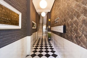 Un pasillo con piso a cuadros, una escalera y un letrero en la pared.