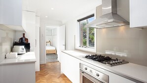 A modern kitchen with white cabinetry, a gas stove, and a window providing natural light.
