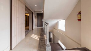 Un pasillo moderno de hotel con piso de mármol, paneles de madera en una pared y un extintor colgado.