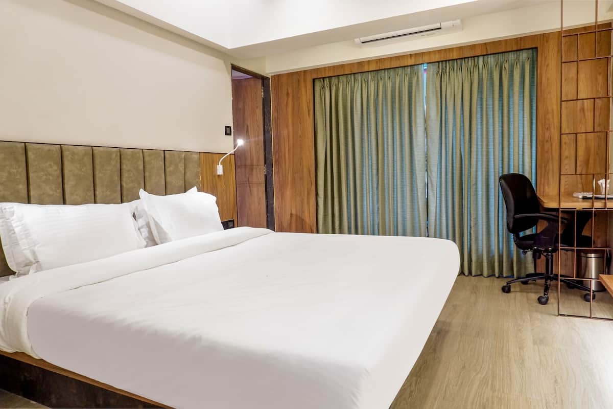 A hotel room with a large bed, a desk with a chair, and a wooden headboard.