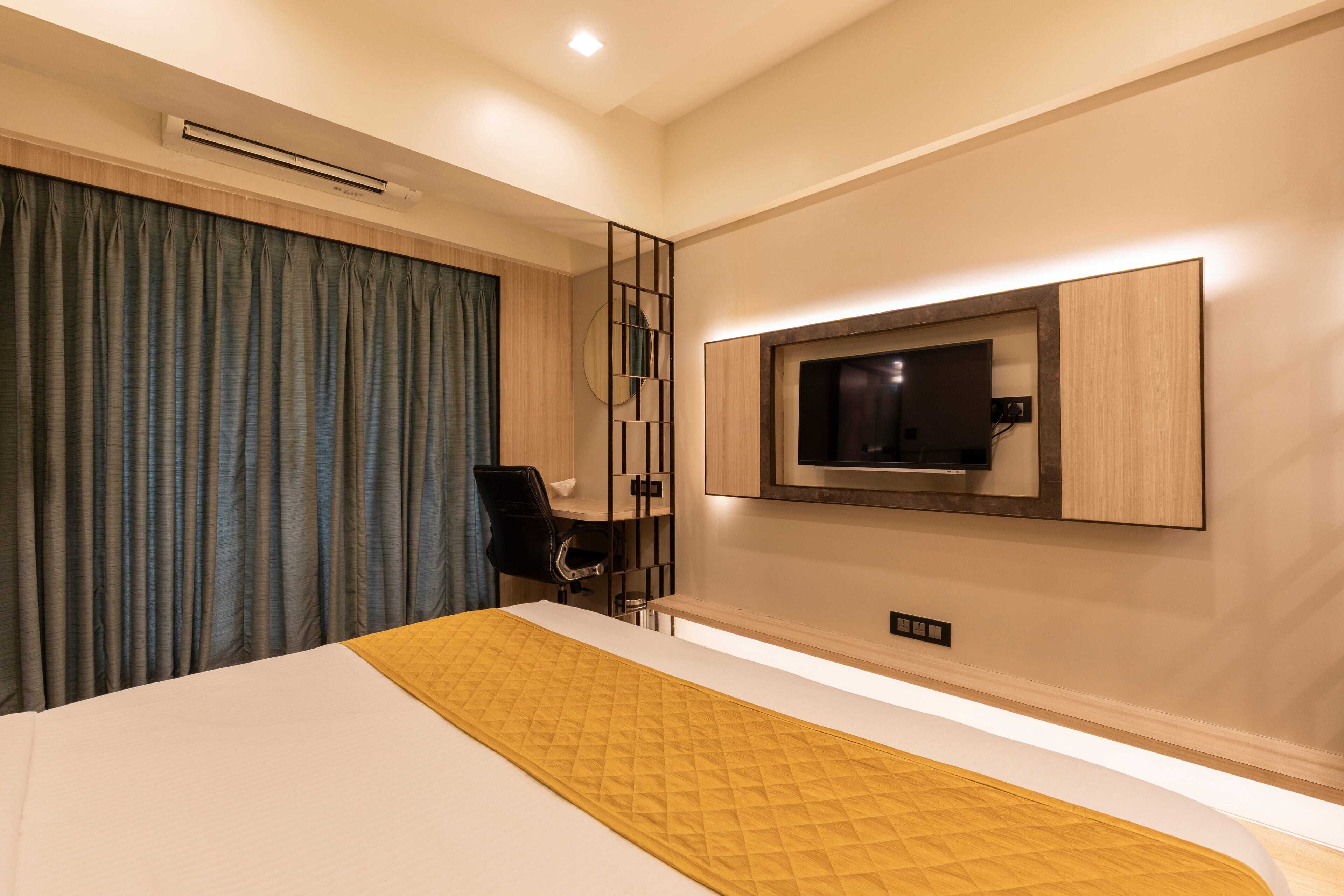 Una habitación de hotel moderna con una cama grande, un televisor montado en la pared y un escritorio con una silla.