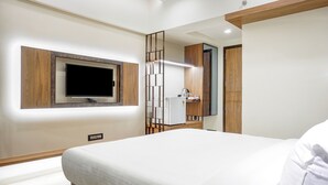 Un dormitorio moderno con una cama grande, un televisor montado y un armario de madera.