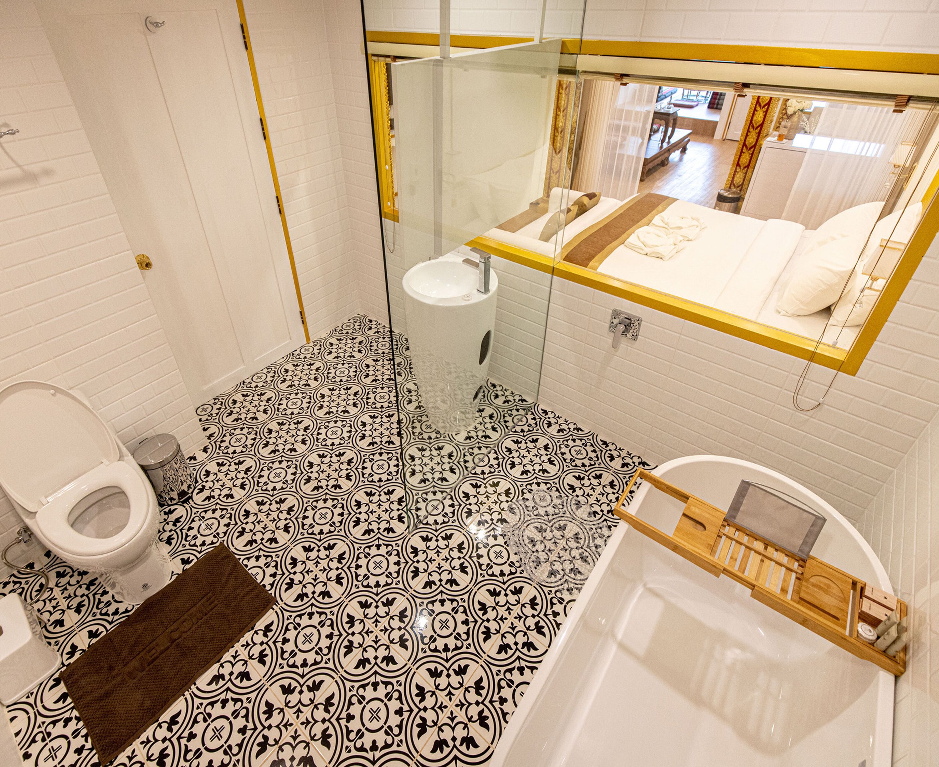 A bathroom with a black and white patterned floor, a white toilet, a sink, and a bathtub with a wooden shelf.