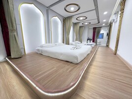 Una habitación de hotel moderna con una cama grande, suelo de madera y un banco curvo.