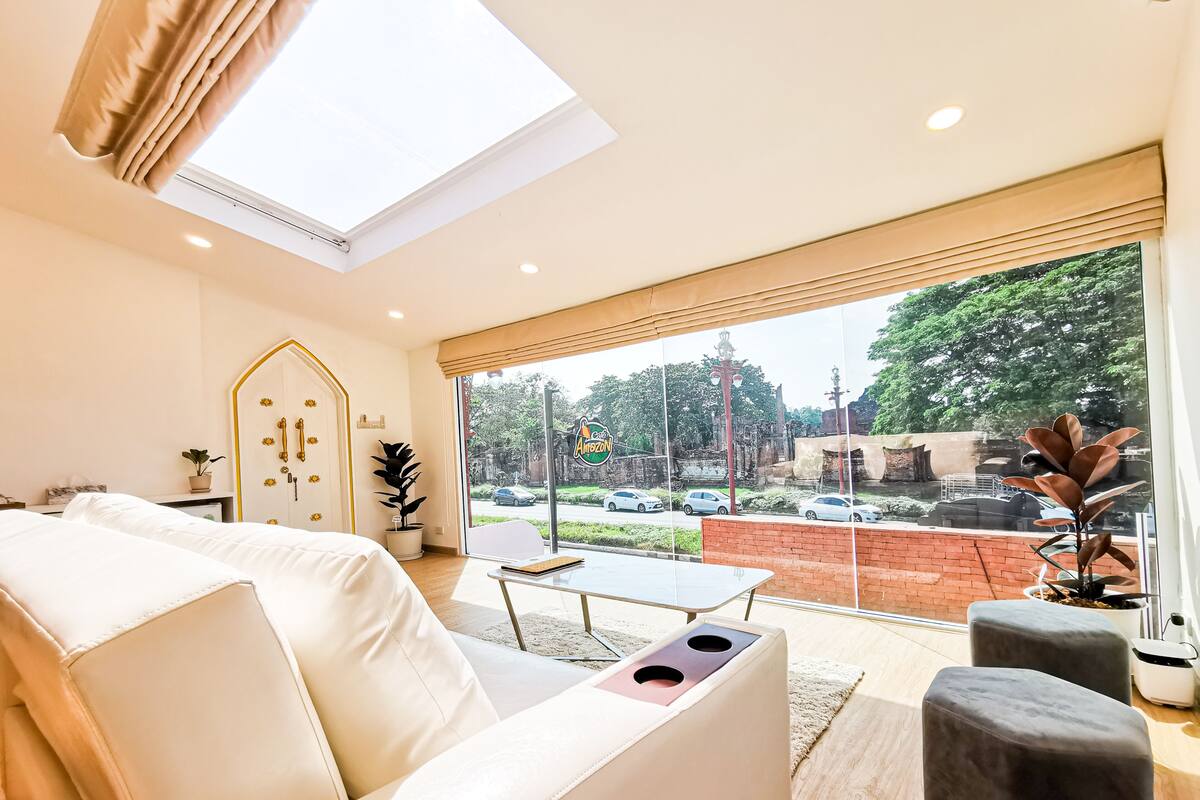 Un salon moderne avec un canapé, une table basse et une vue sur une rue animée, avec des voitures et de la verdure à l'extérieur.