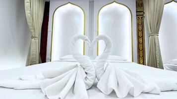 A hotel room with a bed, two large arched windows, and curtains.