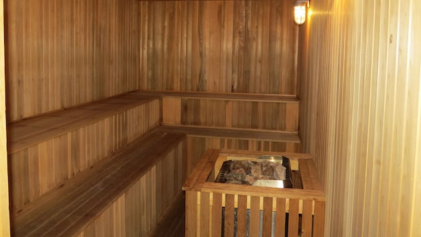 Una sauna de madera con bancos y un cuenco de piedra.