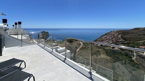 A terrace with a clear view of the sea and a hillside village.