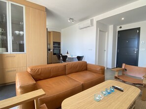 A modern living room with a leather sofa, a wooden coffee table, and a dining area with a table and chairs.
