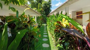 Un sendero con piedras para pisar que atraviesa un exuberante jardín con diversas plantas tropicales.