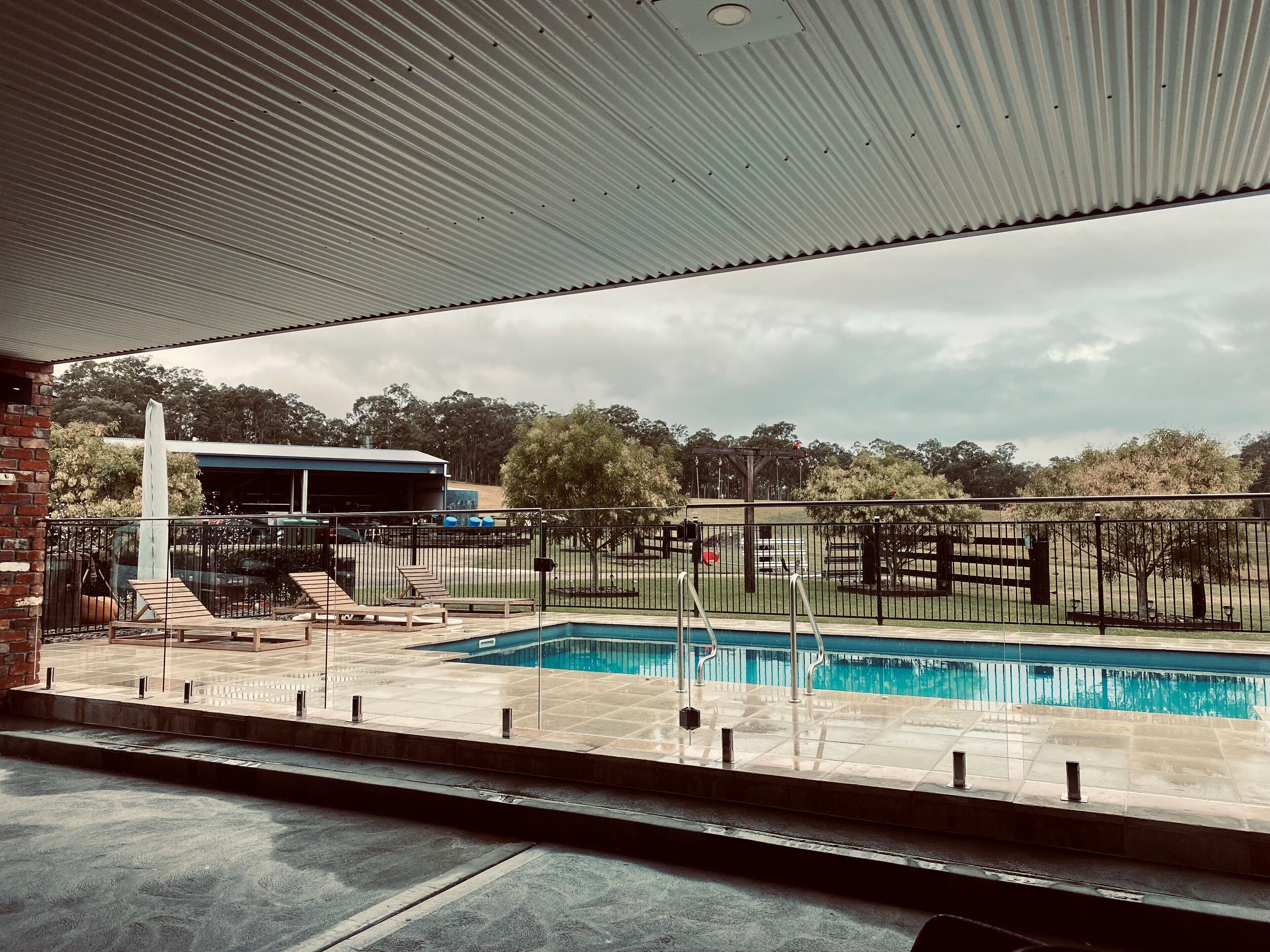 A pool area with a covered seating area, a gazebo, and a fenced play area.