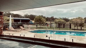 Un espace piscine doté d’un coin salon couvert, d’un belvédère et d’une aire de jeux clôturée.