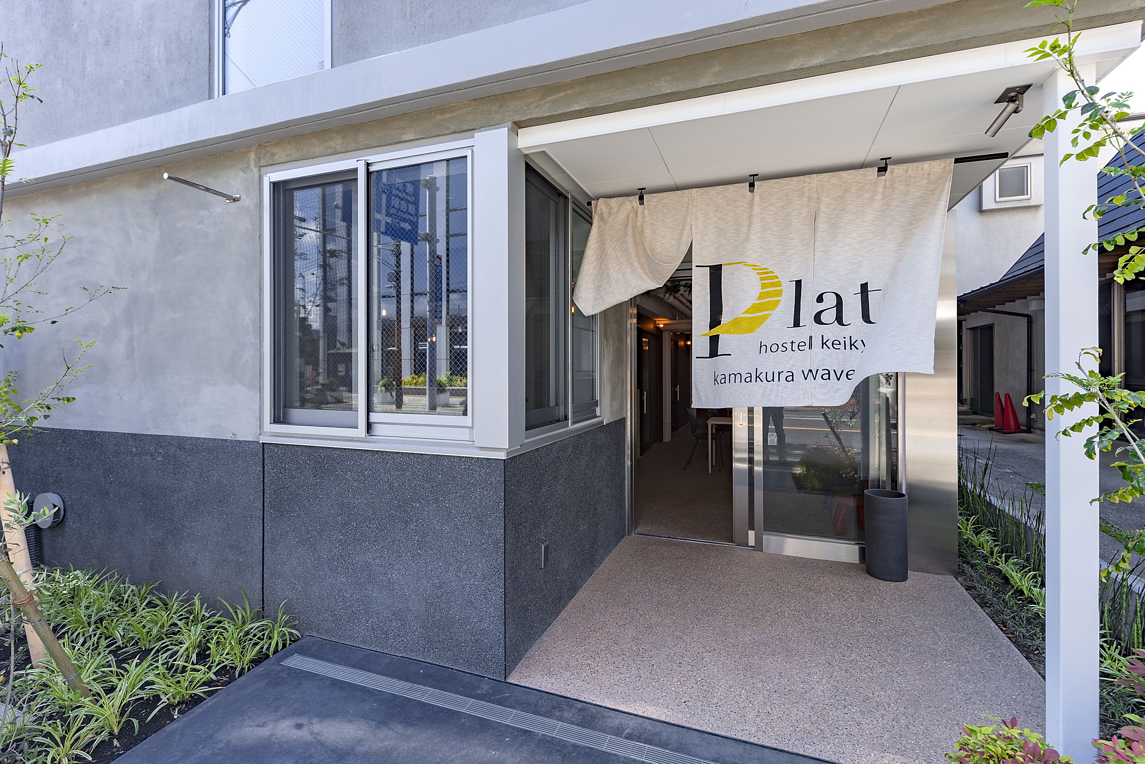 A hostel entrance with a sign reading "Ilat Hostel Keik, Kamakura Wave".