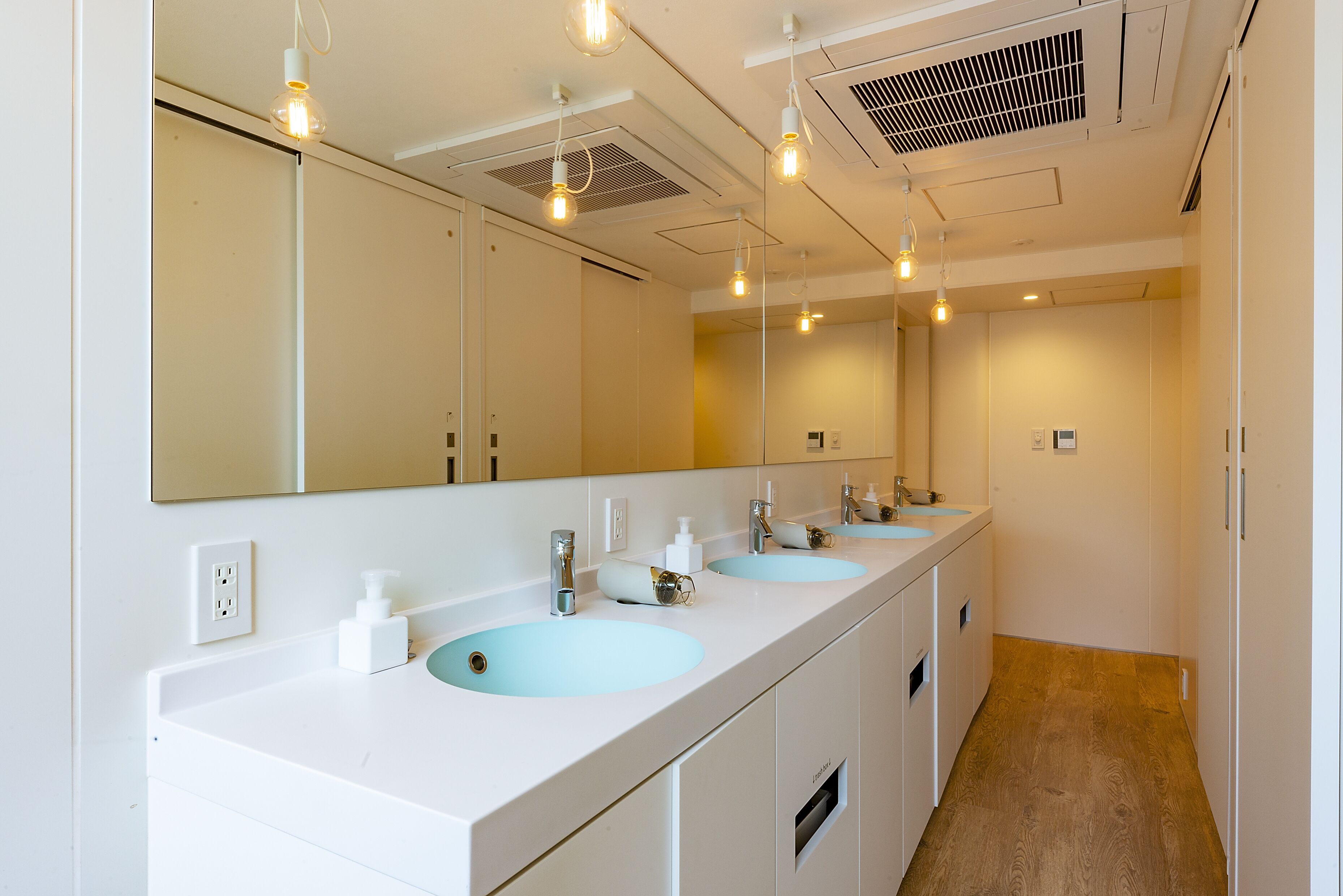 A modern bathroom with two sinks, a large mirror, and overhead lighting.
