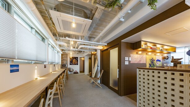 Ein modernes Interieur mit einem langen Holztisch und Stühlen, freiliegenden Rohren und einer Holzauskładung mit Gittermuster.