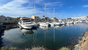 A marina with multiple boats docked, surrounded by buildings and a clear sky. - Cozy Air-Conditioned Apartment for 2 with Terrace, Near Beach, Fully Equipped Kitchen (Cap d'Agde naturisme)