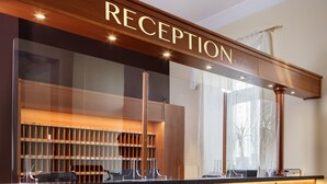 A reception area with a wooden reception desk, a glass partition, and a counter with numbered lockers. - Reitenberger Spa Medical (Marianske Lazne)