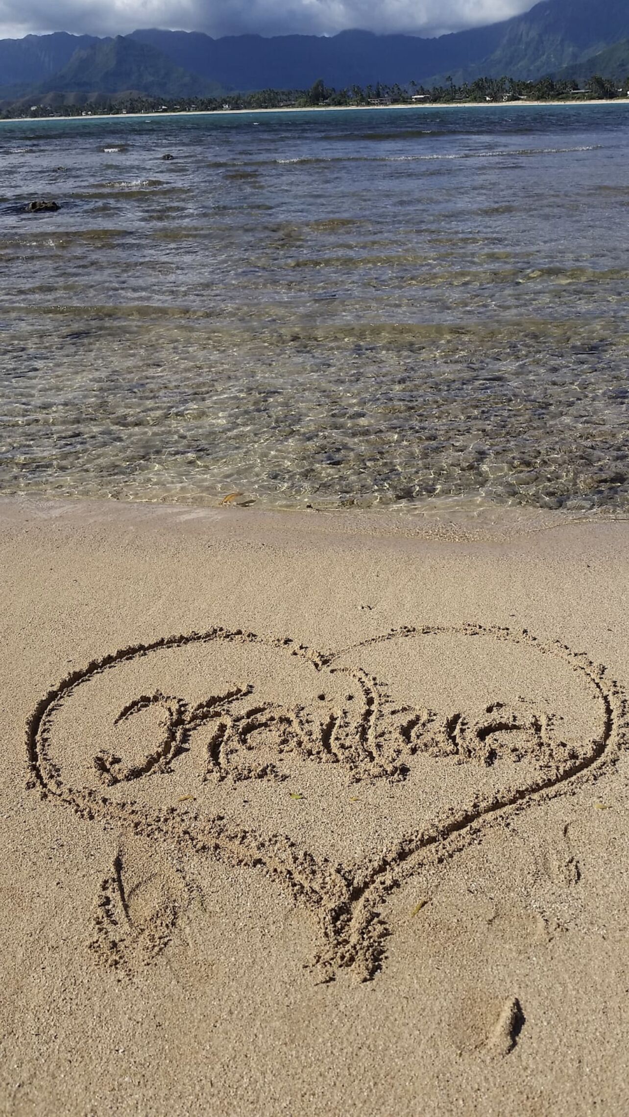 Une plage à l’eau claire, sur laquelle on a dessiné un cœur dans le sable.