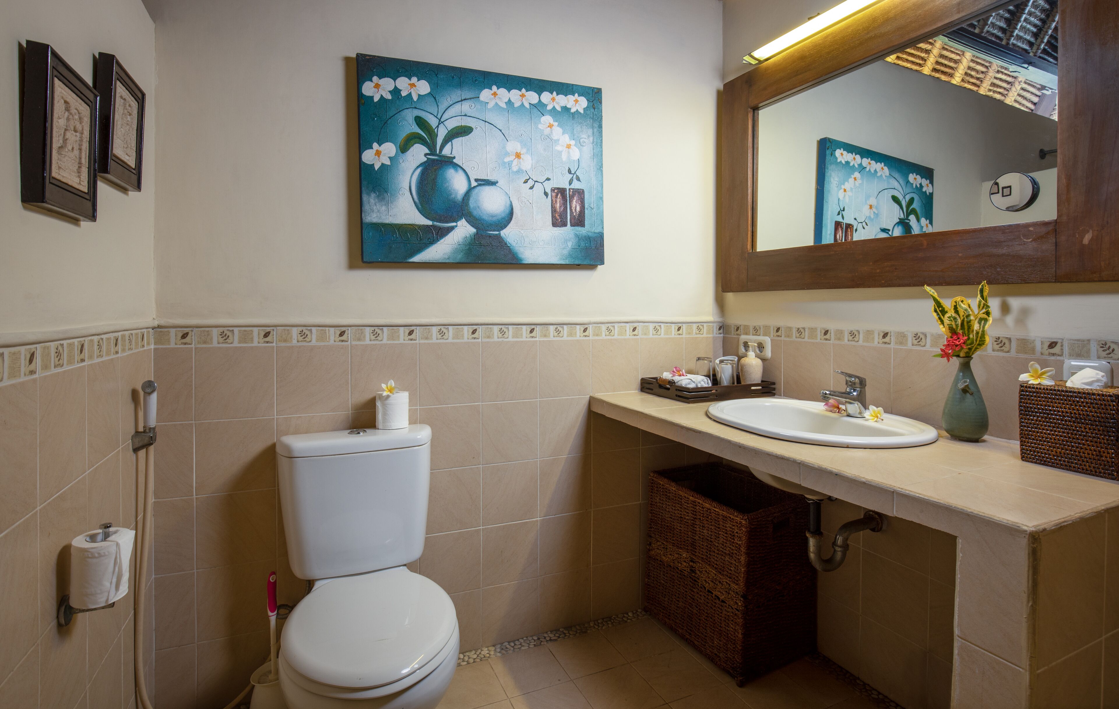 Un baño con inodoro, lavamanos y espejo sobre él.